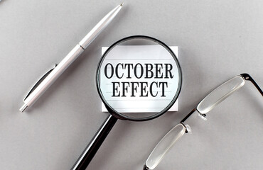 Word OCTOBER EFFECT on sticky through magnifier on grey background