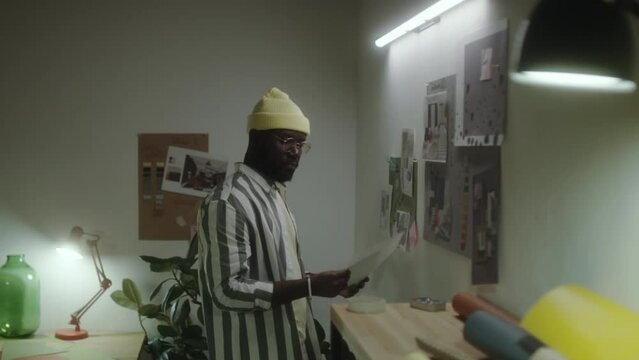 African American Artist Attaching Handmade Collage To Wall While Preparing Inspiring Mood Board In Creative Studio