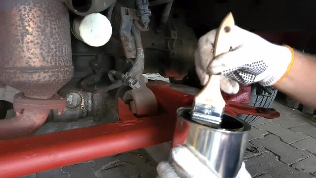 Maintenance of the old car chassis, hand-painted engine compartment of the sleds with a brush with a black anti-corrosion agent