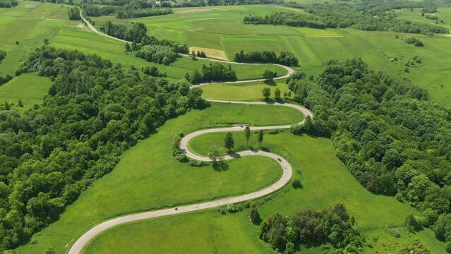Aerial drone view of winding road between green fields