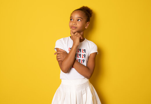 Suspicious thoughtful young african american girl keeping hand on her face as if trying hard to remember something important. Human face expressions and emotions.