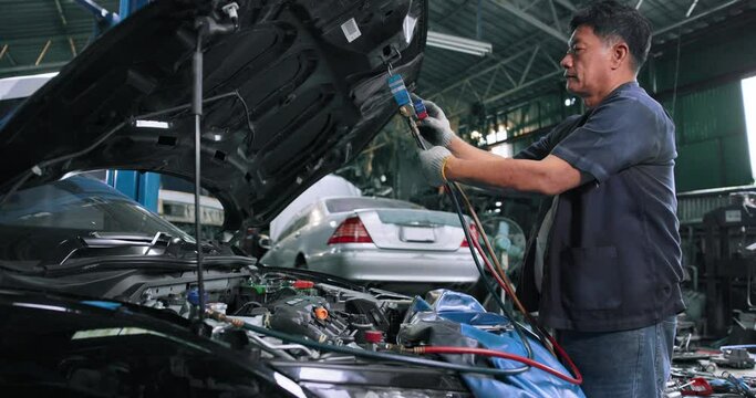 Car mechanic repairing the engine with a wrench, car service A mechanic inspects the engine of an automobile.