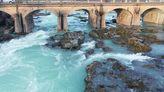 Stains on the old arch bridge over blue river flowing through beautiful rocky landscape. Aerial drone view of Cijevna (Cem, Cemi) stream in Montenegro, Europe.
