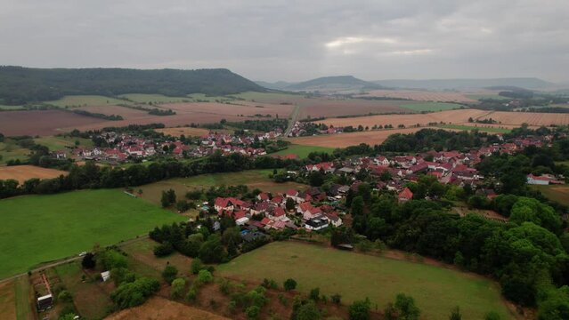 Aer ial view of a German village surrounded by meadows, farmland and forest in Germany.