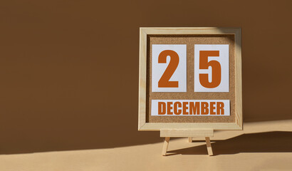December 25th. Day 25 of month, Calendar date. Cork board, easel in sunlight on desktop. Close-up,...