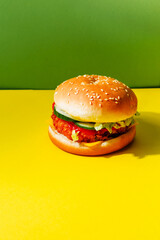 A delicious fish burger with vegetables on a yellow background with space for text. Creative concept of fast food. Stylish banner and advertising of food delivery