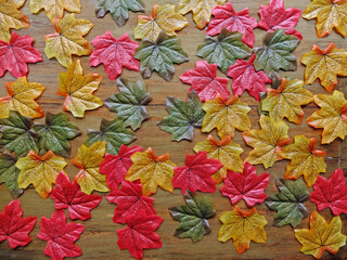 Multicolored autumn artificial leaves scattered over wooden background