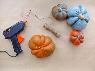 Artificial alabaster pumpkins, hot gun and rope lie on a beige background
