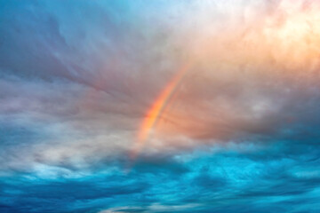 Fototapeta na wymiar rainbow over Cumulus and cirrus cloudy dramatic gloomy sky before evening thunderstorm