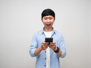Asian man blue shirt using and checking smart phone feels amazed isolated
