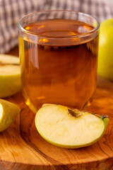Glass of Apple juice on wooden cutting board with chopped and full apple