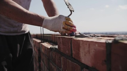 builder lays brick wall, hands close-up