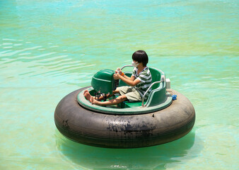 Little asian boy having a fun in water park with Bumper boats