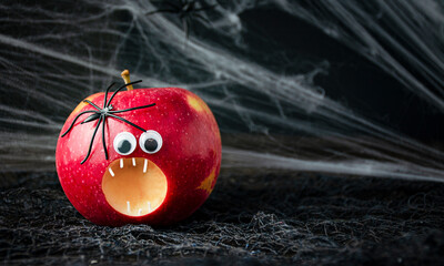 Halloween background. Scary apple with spiders on a dark background. Halloween food. Banner. Copy...