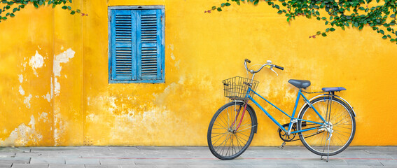 Old bicycle parking against yellow wall in Vietnam