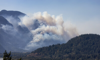 Fototapeta premium BC Forest Fire and Smoke over the mountain near Hope during a hot sunny summer day. British Columbia, Canada. Wildfire natural disaster