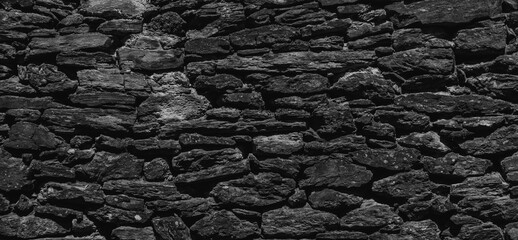 wide dark stone wall texture. Empty black stone wall background.