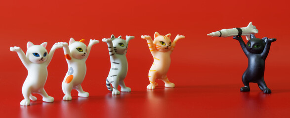 Toy dancing kittens from a meme on a red background. A black kitten threatens other kittens with a rocket or projectile. Nuclear blackmail. Apocalyptic anti-war concept.
