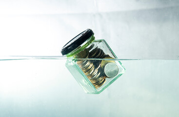 Money and financial risk concept with coins sinking into water