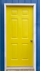 Yellow house door set in blue wall.