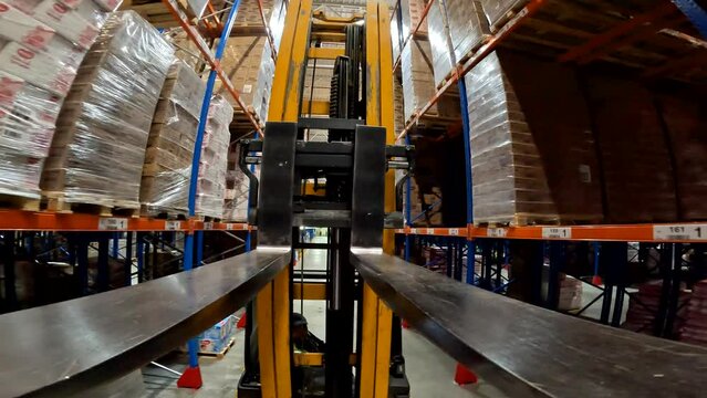 Modern forklift in a large warehouse. Forklift fork close-up. The load lifter rides on the warehouse pov.