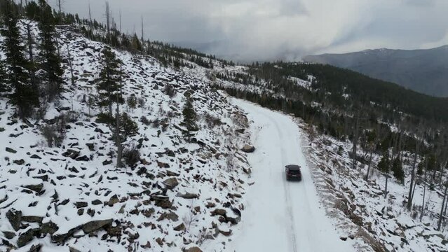 Flying a drone behind a car in the winter mountains. jeep grand cherokee wk2 on snow in the forest