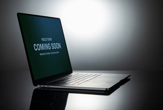 Coming soon banner on laptop screen showing website under construction sign