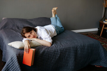 A woman is lying on a bed with a book