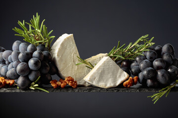 Cheese camembert with walnuts, blue grapes, and rosemary.