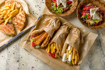 skepasti with chicken, assorted gyros on plate, gyros with chicken, gyros with feta cheese, gyros with halumi cheese, greek salad on stone table top view, Greek cuisine
