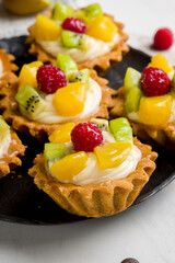 cake basket with cream and fruit on white marble table vertical