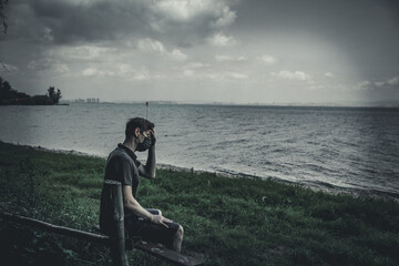 Man wearing mask in pain and is sitting at a bench