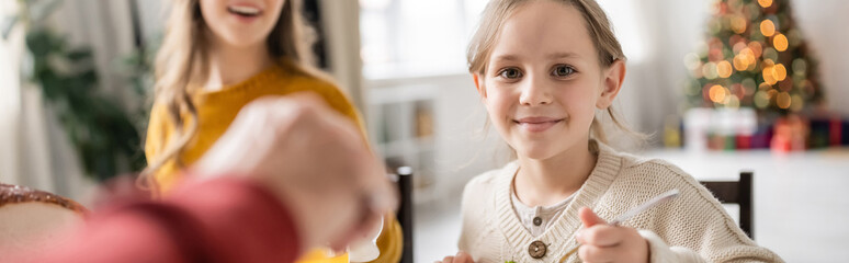 Smiling kid looking at camera during thanksgiving celebration with family at home, banner