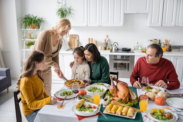 Interracial family looking at thanksgiving pie during festive dinner at home