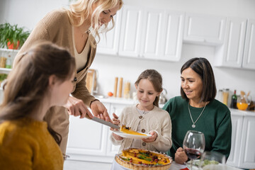 Obraz na płótnie Canvas Woman putting thanksgiving pie on plate near interracial family at home