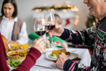 smiling man clinking wine glasses with daughter during festive thanksgiving dinner