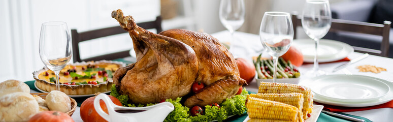 delicious roasted turkey near grilled corn and blurred pumpkin pie on table with thanksgiving...