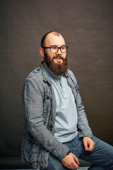 lifestyle successful young man with glasses , beard, fashionable denim jacket looking forward,male portrait in the Studio on a uniform background.