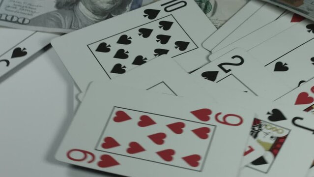 $100 Bills Cascade Onto Playing Cards Rotating White Background 4K