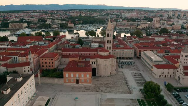 Zadar, Croatia - 4K Flying away up high from the Forum of the old town of Zadar with Church of St. Donatus and the bell tower of the Cathedral of St. Anastasia on a summer morning with golden sunrise