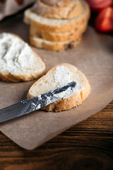bread with butter, cream cheese, eggs next to tomatoes and a knife. breakfast on a wooden table