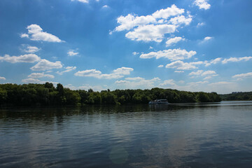 A steamer floating on a huge river and floating clouds above the river
