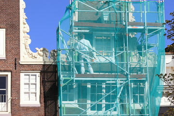 Amsterdam Prinsengracht Canal House Gable Close Up with Green Construction Screen and Worker During Renovation Works, Netherlands