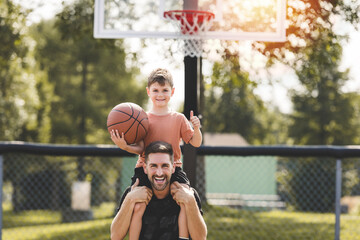 man and young boy playing basketball on a court, teaching little player and spending time outdoors