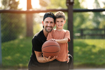 man and young boy playing basketball on a court, teaching little player and spending time outdoors