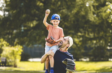 Father and son playing baseball in sunny day at public park