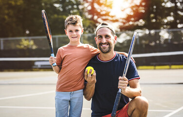 father and son play tennis on a summer day