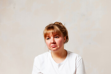 Frustrated 30-year-old girl on  light background.