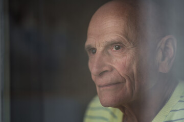 Granddad looking through window glass close side view. Solitude concept.