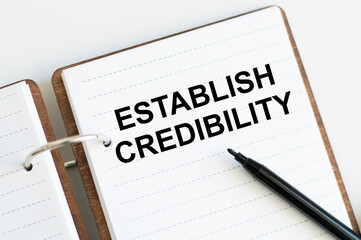 ESTABLISH CREDIBILITY text on sticker with pen on the black background